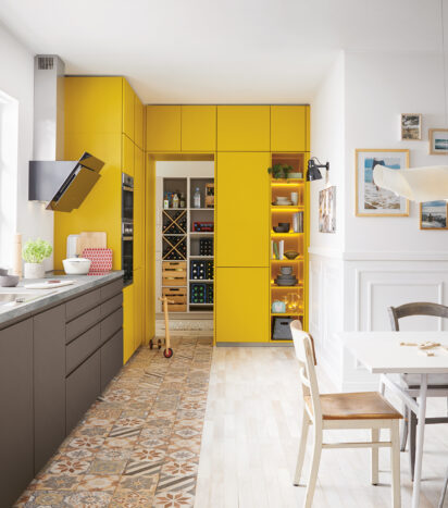 Kitchen with corner yellow cupboard space and window facing cooking area.