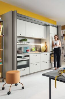 Compact kitchen side view open doors with standing woman