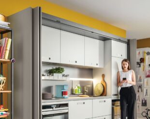Compact kitchen side view open doors with standing woman