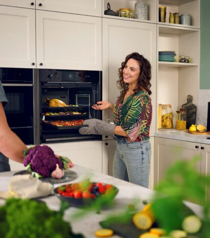 Woman and Man Chatting Using Neff Oven with Retractable Door