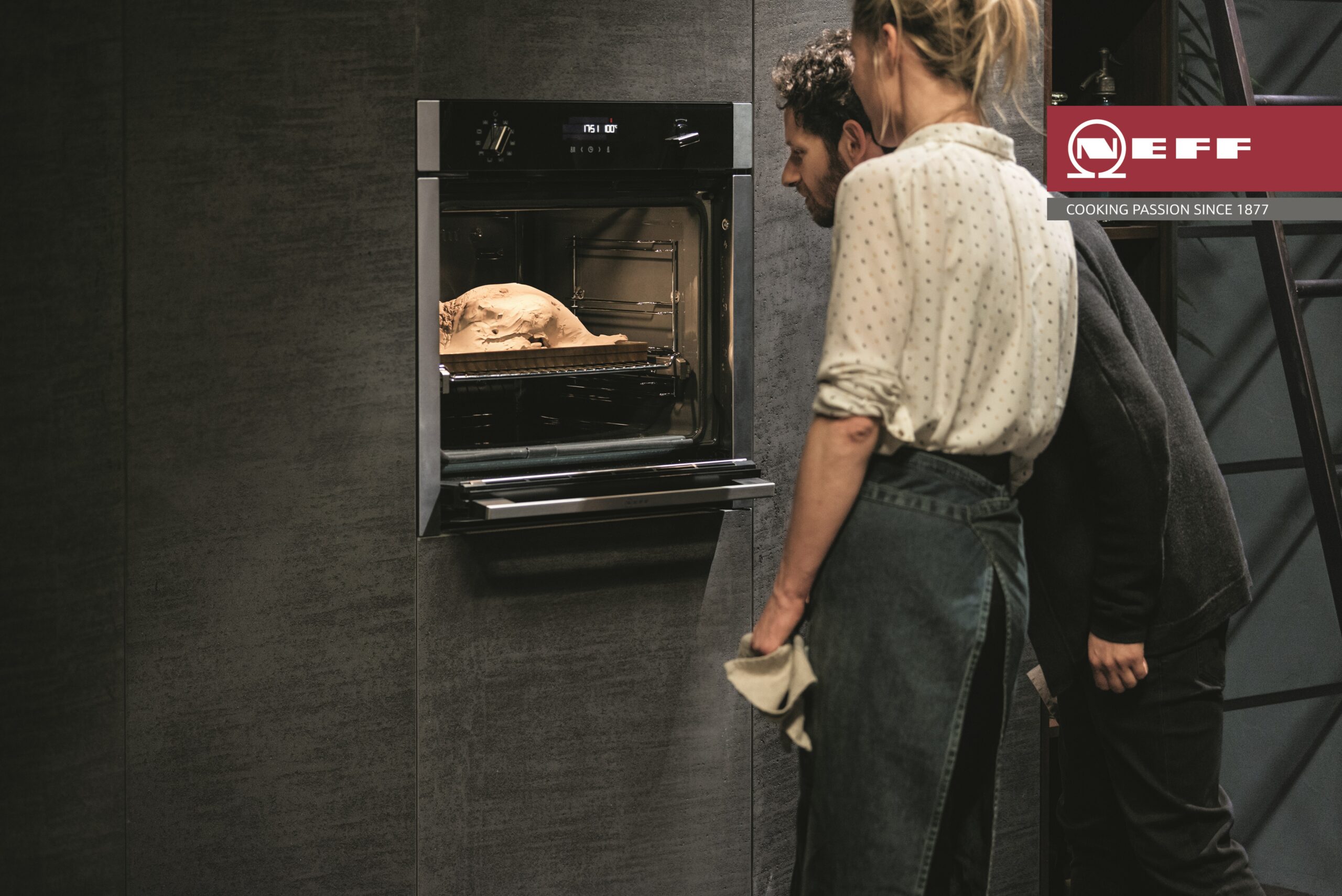 Men and Woman looking at Chicken in Neff Single Oven with Retractable Door