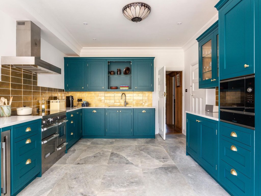 Teal in-frame cabinetry, gold splashback tiles and white worktops in Tim’s Hove kitchen