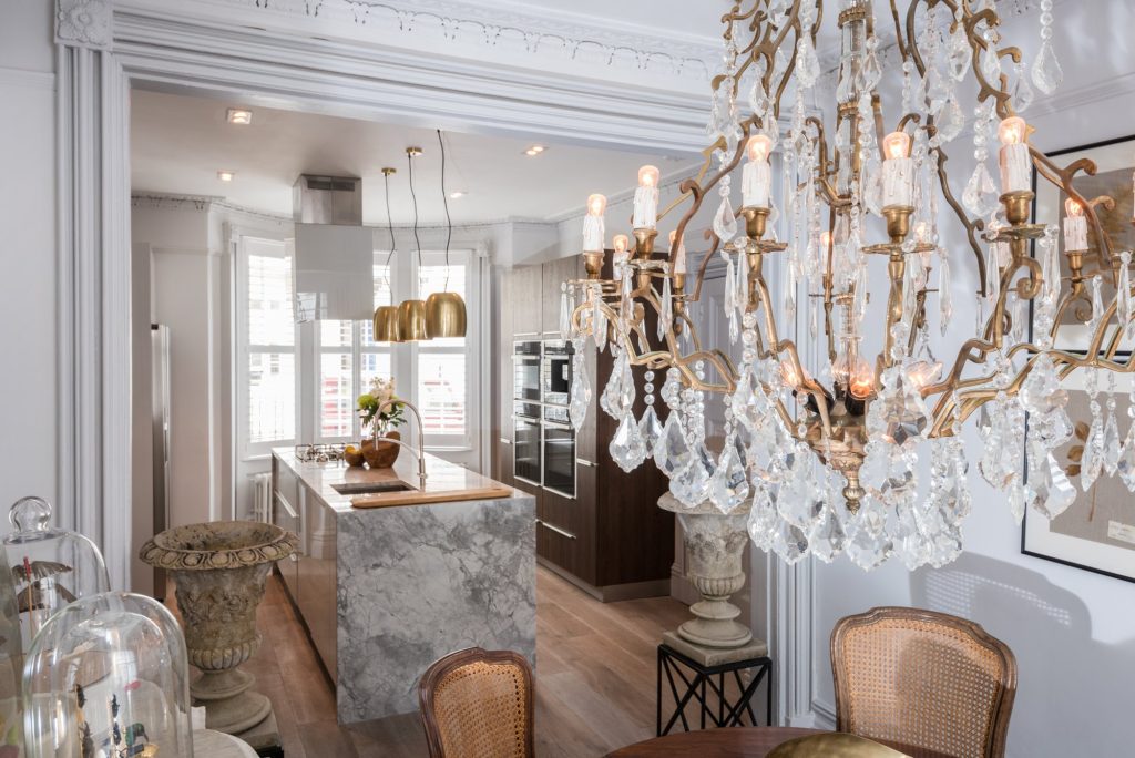 Crystal chandelier and period dining furniture alongside the contemporary kitchen