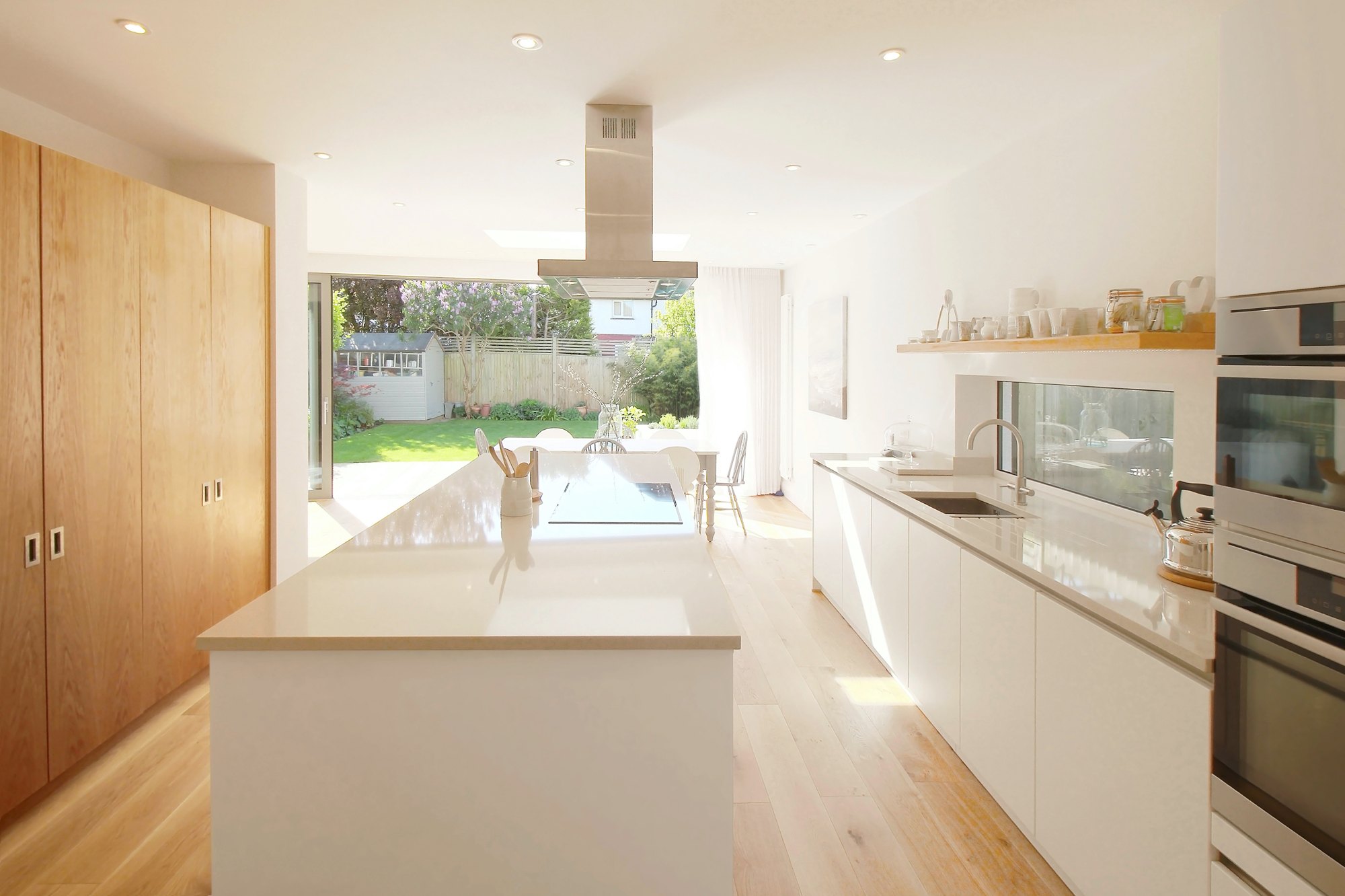 Emma’s white kitchen in Hove with oak cabinetry and an island overlooking the garden